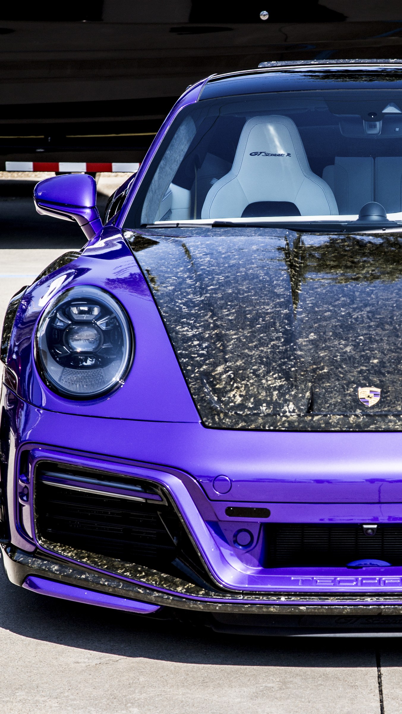 Close-up of a purple Porsche with light reflecting across its carbon-fiber hood